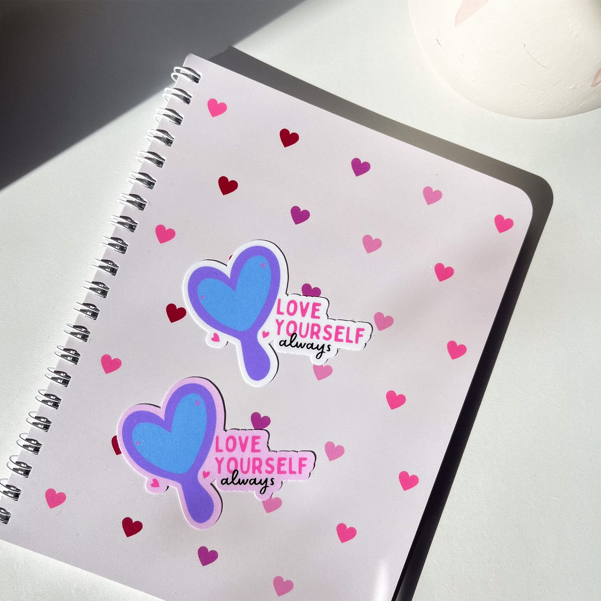 Love Yourself Always mirror sticker on top of pink hearts notebook from My Rainbow Journal