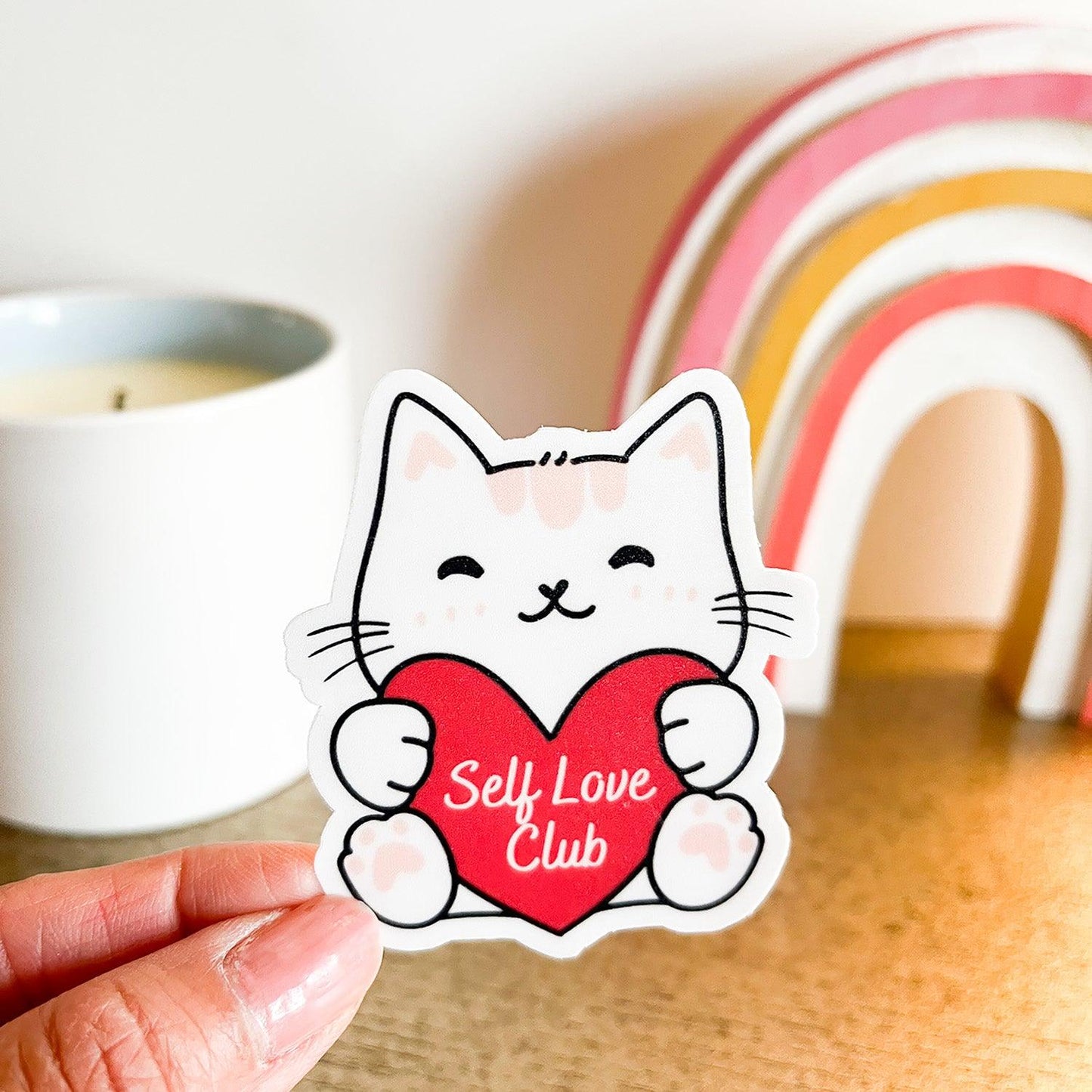Self Love Club cat sticker in hand