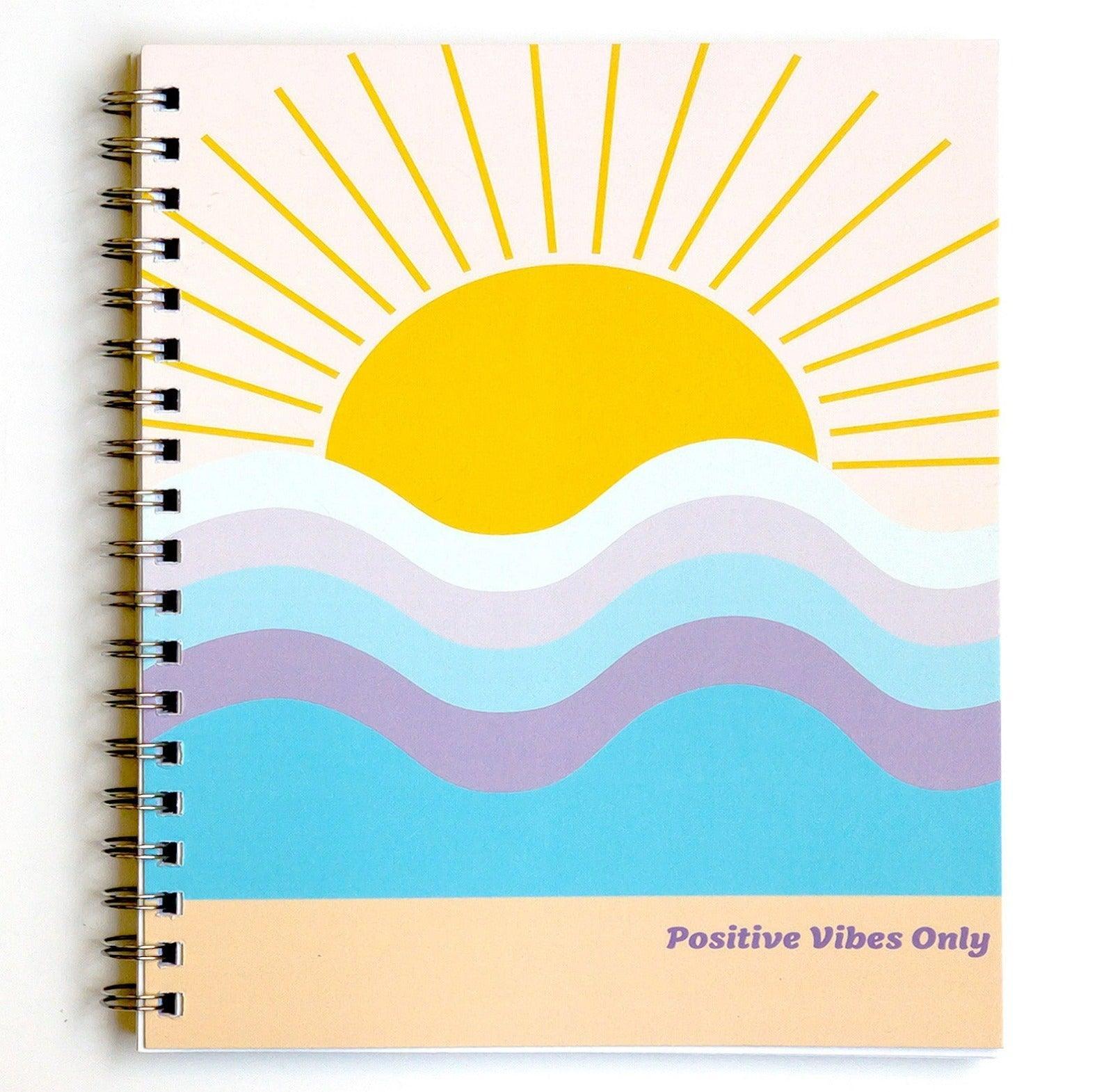 Positive Vibes Only Journal - The front cover features a beautiful sun coming over the horizon as waves of blue and purple flow at the beach. 