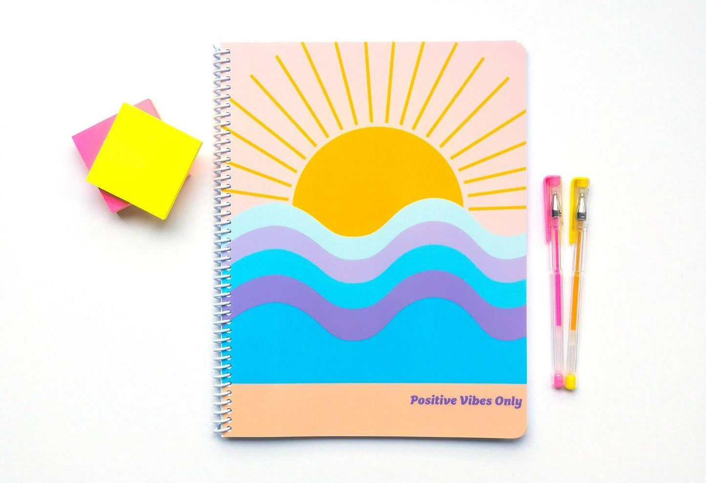 Positive Vibes Only Notebook flat lay features notebook cover with a sun coming over the horizon at the beach with phrase Positive Vibes Only.
